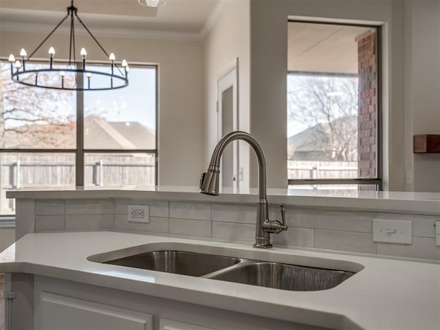 kitchen featuring sink, hanging light fixtures, crown molding, a chandelier, and white cabinets