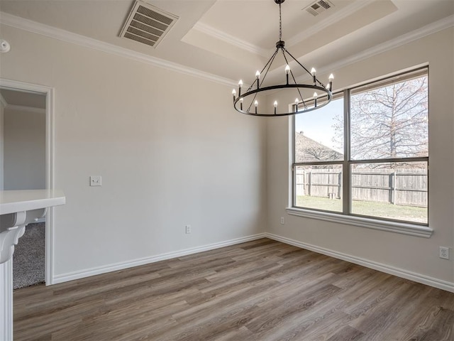 unfurnished dining area featuring a notable chandelier, wood-type flooring, ornamental molding, and a tray ceiling