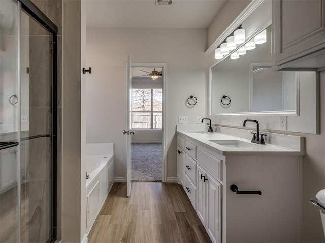 bathroom with wood-type flooring, vanity, ceiling fan, and a tub