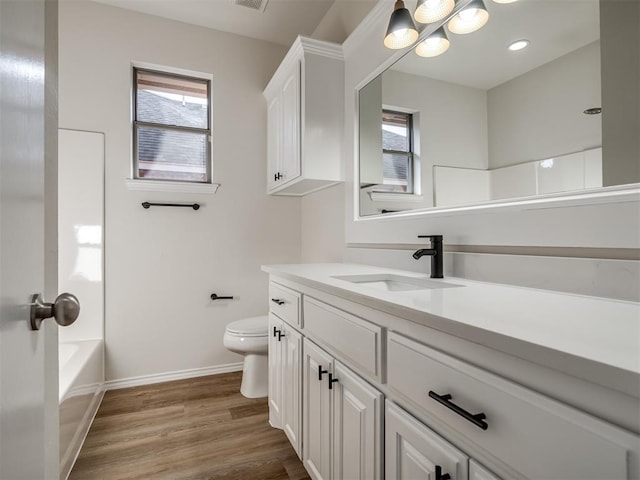 full bathroom with toilet, vanity, a healthy amount of sunlight, and hardwood / wood-style flooring