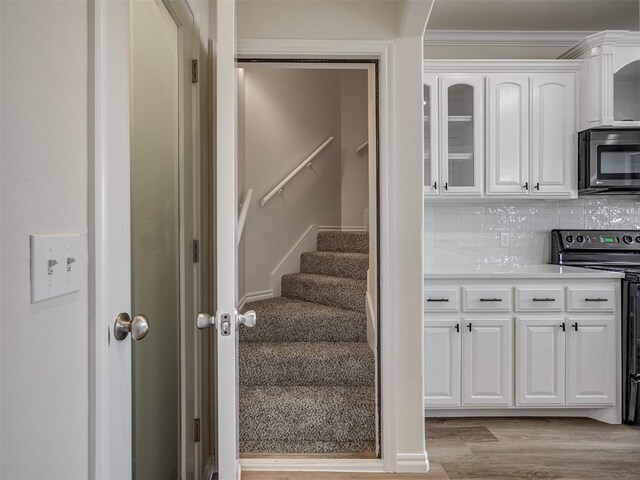 stairs with hardwood / wood-style floors and ornamental molding