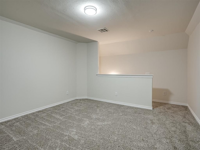 carpeted empty room with a textured ceiling and lofted ceiling