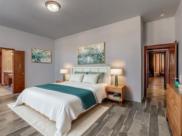 bedroom featuring ensuite bath and dark hardwood / wood-style flooring