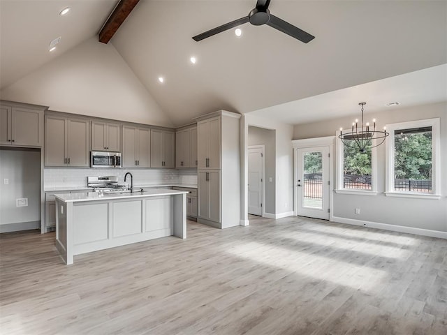 kitchen with a kitchen island with sink, light wood-type flooring, ceiling fan with notable chandelier, and appliances with stainless steel finishes