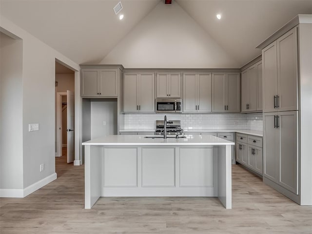 kitchen featuring gray cabinets, a kitchen island with sink, sink, and appliances with stainless steel finishes