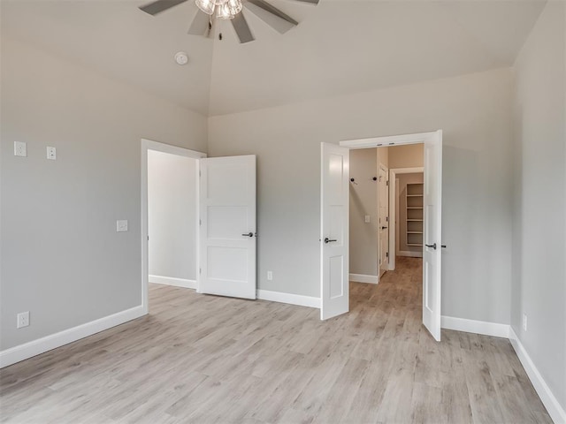 unfurnished bedroom featuring a walk in closet, ceiling fan, light hardwood / wood-style flooring, a closet, and lofted ceiling