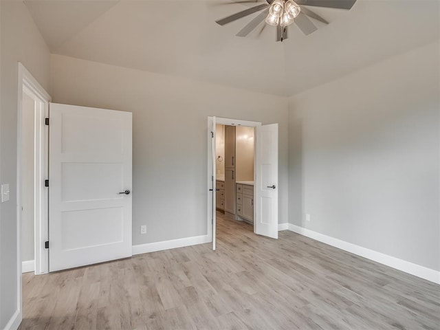 unfurnished bedroom with ceiling fan, light wood-type flooring, connected bathroom, and vaulted ceiling