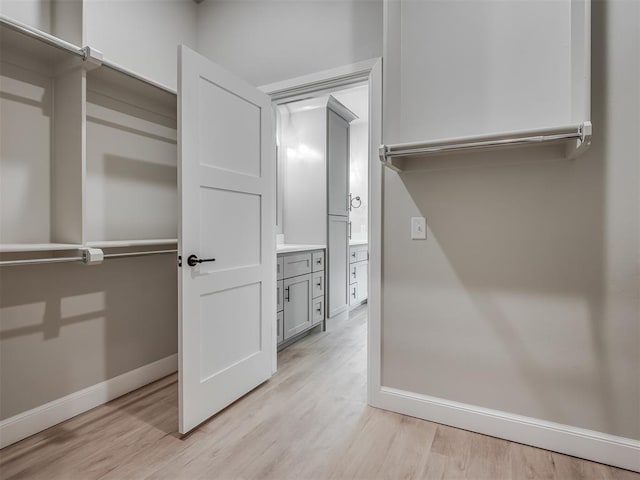 walk in closet with light hardwood / wood-style floors