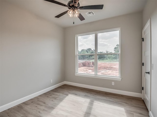 empty room with ceiling fan, plenty of natural light, and light hardwood / wood-style flooring