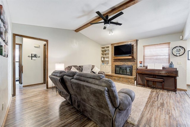 living room with hardwood / wood-style flooring, built in shelves, a fireplace, ceiling fan, and vaulted ceiling with beams