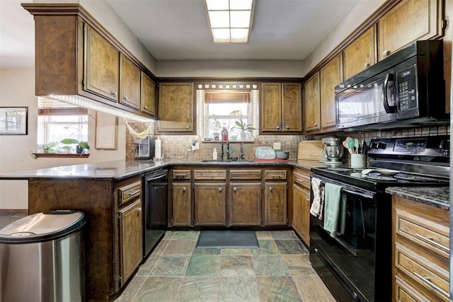 kitchen with sink, tasteful backsplash, kitchen peninsula, dark stone counters, and black appliances