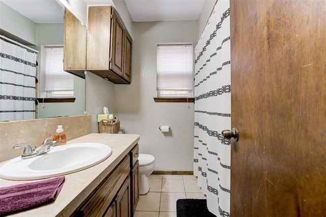 bathroom with a healthy amount of sunlight, vanity, tile patterned floors, and toilet