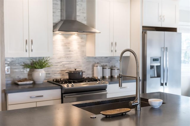 kitchen with white cabinets, wall chimney exhaust hood, backsplash, and stainless steel appliances