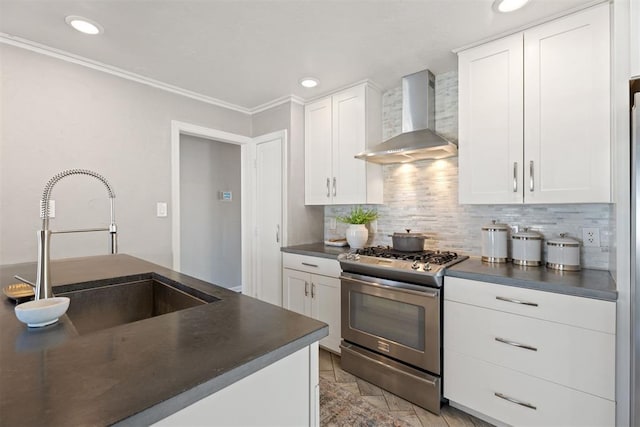 kitchen featuring backsplash, sink, stainless steel gas range, wall chimney exhaust hood, and white cabinetry