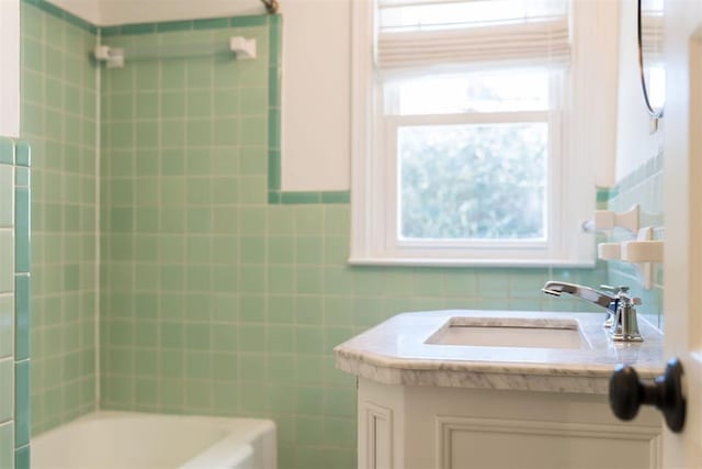 bathroom with shower / tub combination, vanity, and tile walls