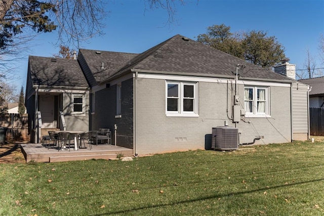 rear view of house with central AC and a yard