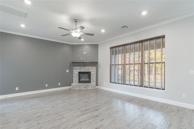 unfurnished living room featuring crown molding, a stone fireplace, light wood-type flooring, and ceiling fan