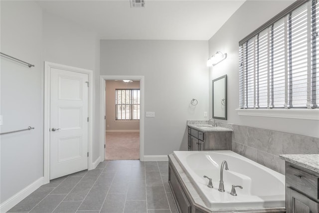 bathroom with a relaxing tiled tub, tile patterned floors, and vanity