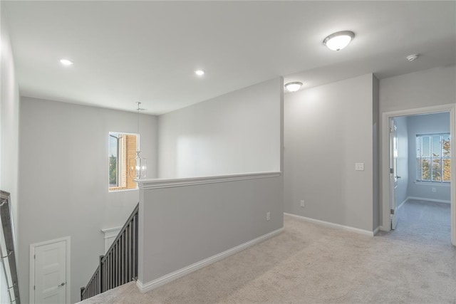 corridor with a healthy amount of sunlight and light carpet