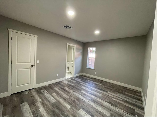 unfurnished bedroom with ensuite bathroom and dark hardwood / wood-style floors