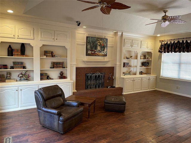 living area with a fireplace, ceiling fan, and dark hardwood / wood-style flooring