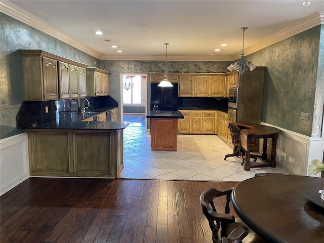 kitchen featuring light wood-type flooring, ornamental molding, pendant lighting, black fridge, and sink