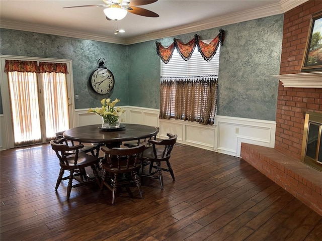 dining space featuring a fireplace, ornamental molding, ceiling fan, and dark wood-type flooring