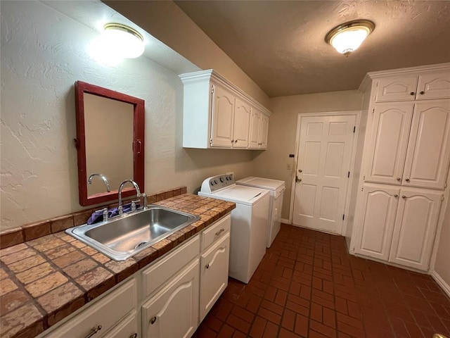 laundry area featuring independent washer and dryer, cabinets, and sink