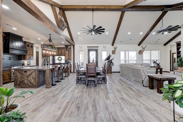 dining room with ceiling fan, beamed ceiling, a healthy amount of sunlight, and light wood-type flooring