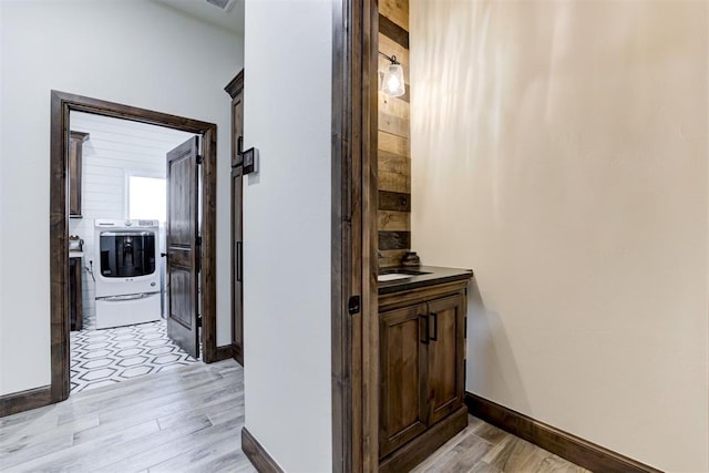 corridor with washer / dryer and light hardwood / wood-style flooring