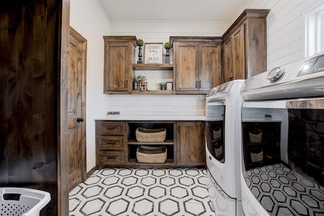 clothes washing area featuring washer and clothes dryer and cabinets