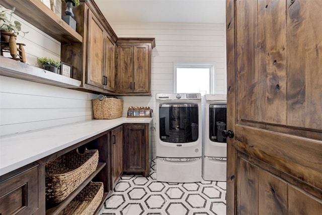 laundry room with washer and dryer, wooden walls, and cabinets