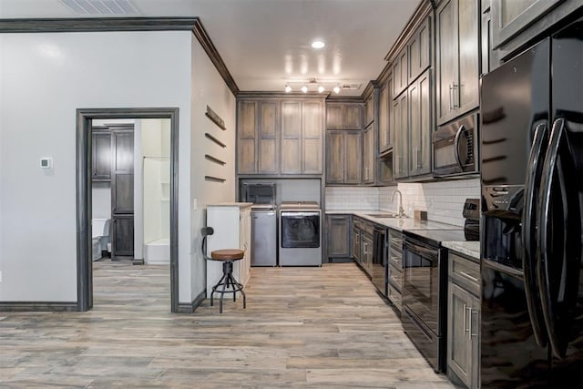 kitchen with backsplash, dark brown cabinets, black appliances, light hardwood / wood-style flooring, and washer / clothes dryer