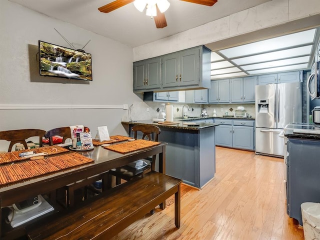 kitchen with sink, tasteful backsplash, kitchen peninsula, light hardwood / wood-style floors, and appliances with stainless steel finishes