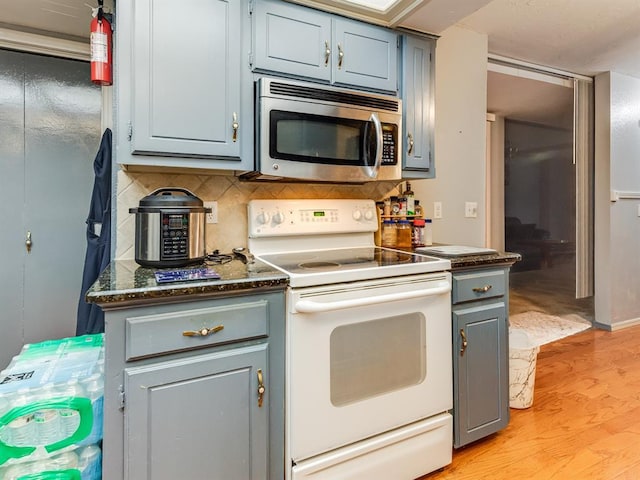 kitchen with white range with electric cooktop, light hardwood / wood-style floors, and backsplash