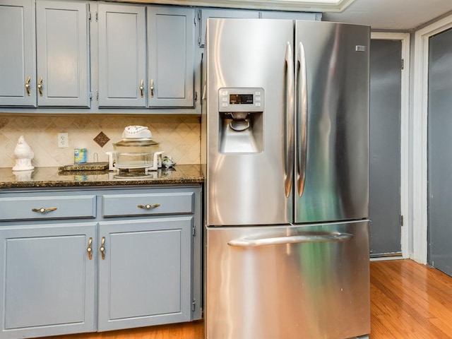 kitchen featuring stainless steel fridge with ice dispenser, tasteful backsplash, and dark stone countertops