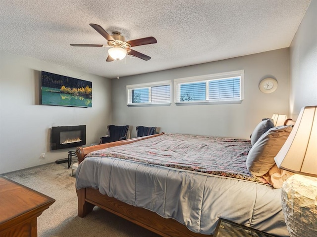 bedroom featuring multiple windows, a textured ceiling, carpet floors, and ceiling fan