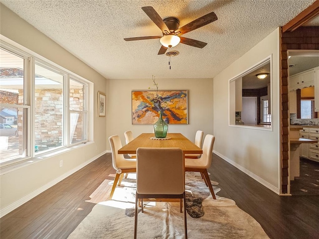 dining area featuring ceiling fan, dark wood-type flooring, and a textured ceiling