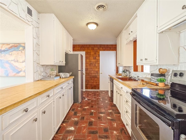 kitchen with sink, white cabinets, a textured ceiling, and appliances with stainless steel finishes