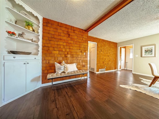 interior space with beam ceiling, dark wood-type flooring, and a textured ceiling