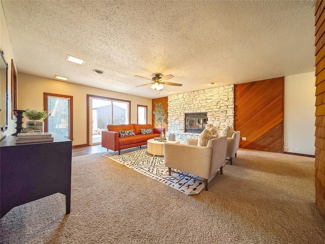 living room featuring a textured ceiling, wood walls, carpet, and a stone fireplace