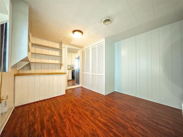 unfurnished living room featuring hardwood / wood-style flooring, built in features, and wood walls