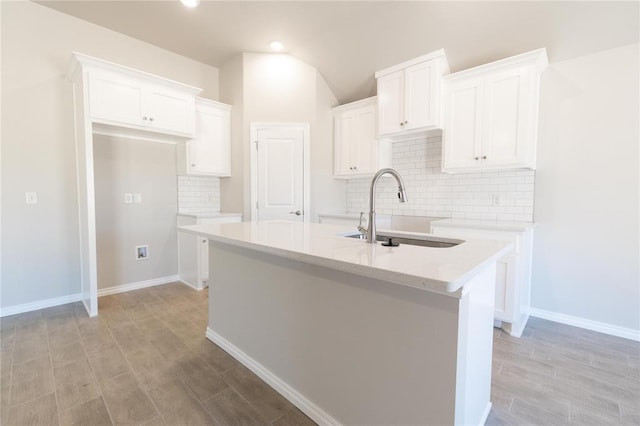 1917 Taines Turn, Norman, OK 73072 - kitchen featuring decorative backsplash, light wood-style floors, an island with sink, white cabinets, and a sink