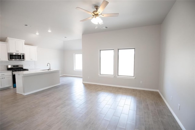 1917 Taines Turn, Norman, OK 73072 - kitchen featuring appliances with stainless steel finishes, open floor plan, a ceiling fan, backsplash, and white cabinets