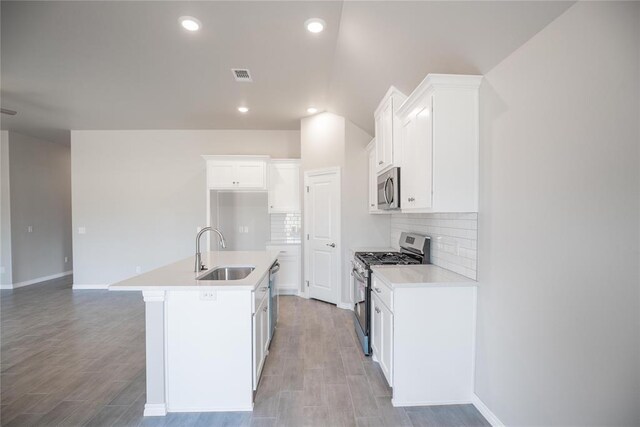 1917 Taines Turn, Norman, OK 73072 - kitchen with appliances with stainless steel finishes, a kitchen island with sink, decorative backsplash, white cabinetry, and light countertops