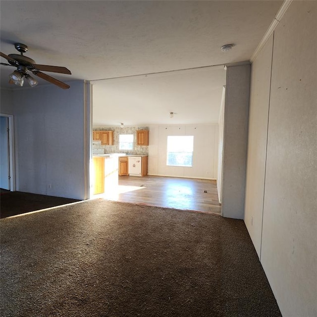 unfurnished living room with light wood-style floors, light colored carpet, and ceiling fan