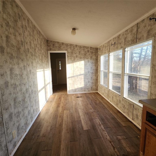 unfurnished room with dark wood-style floors, wallpapered walls, ornamental molding, and baseboards