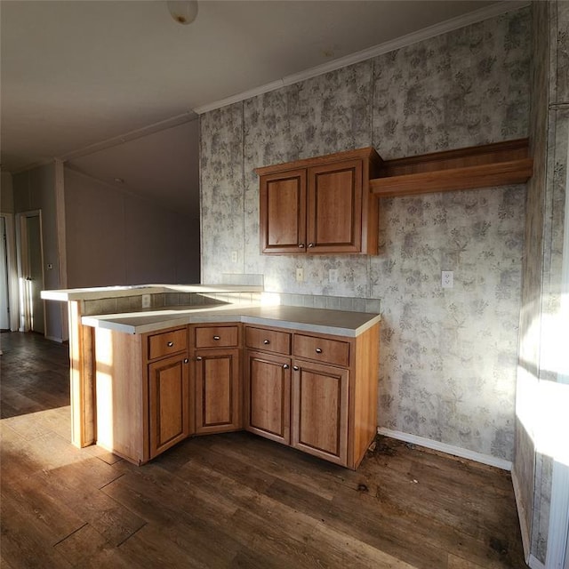 kitchen with dark wood-style floors, brown cabinets, light countertops, a peninsula, and wallpapered walls