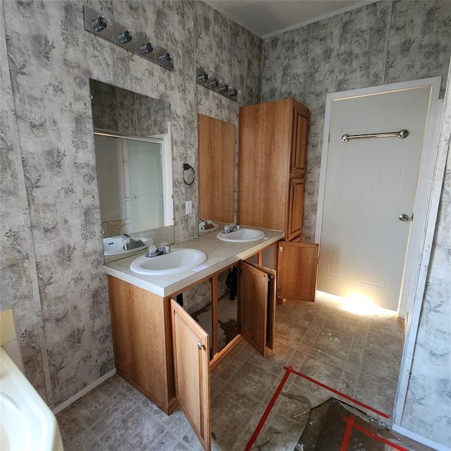 full bath featuring a sink, baseboards, and double vanity