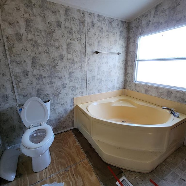 full bathroom with toilet, a bath, and wallpapered walls